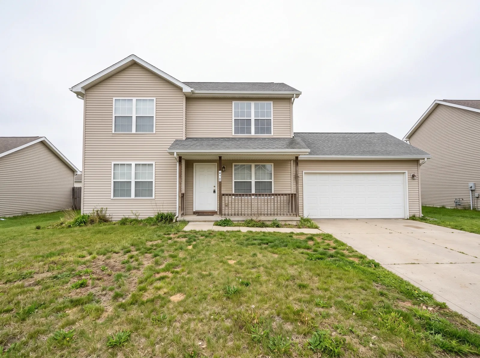 Before: a two-story house with beige vinyl siding, white windows, a grey roof and a white garage door