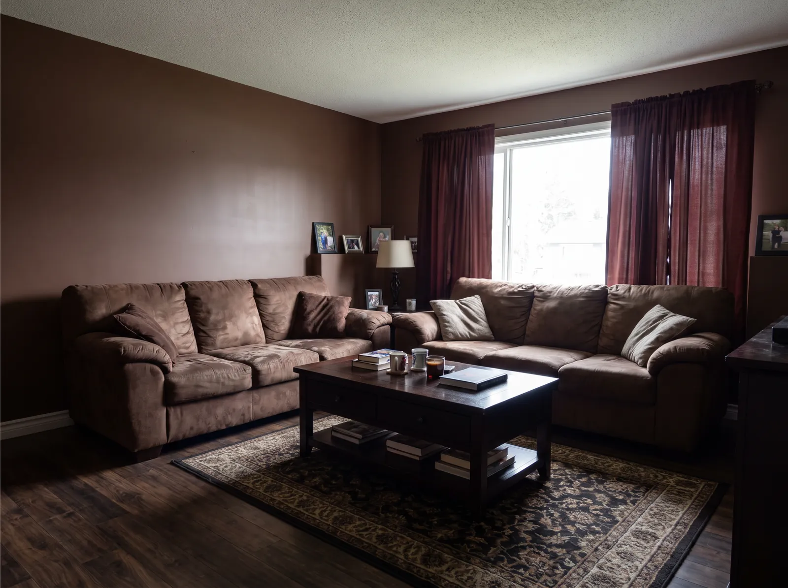 Before: a living room with brown walls, maroon curtains, two brown sofas and a dark patterned rug
