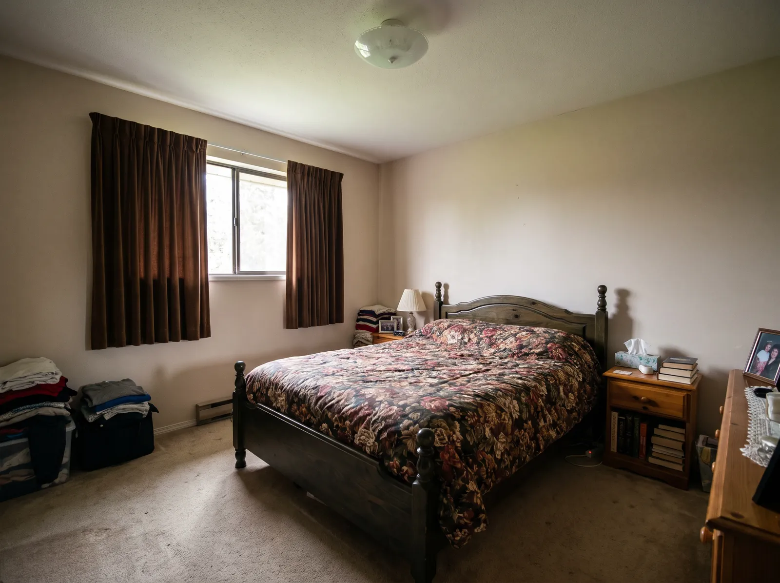 Before: a dim bedroom with brown curtains, a dark pine bed with a floral duvet and clothes piled by the wall