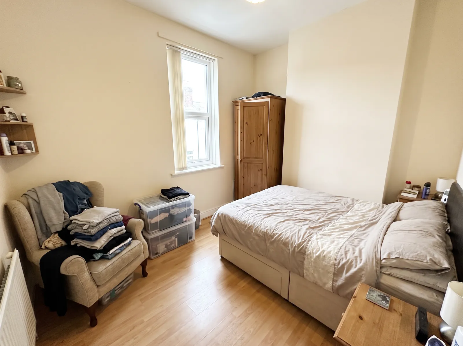 Before: a small bedroom with clothes piled on an armchair, plastic storage boxes and crowded shelves